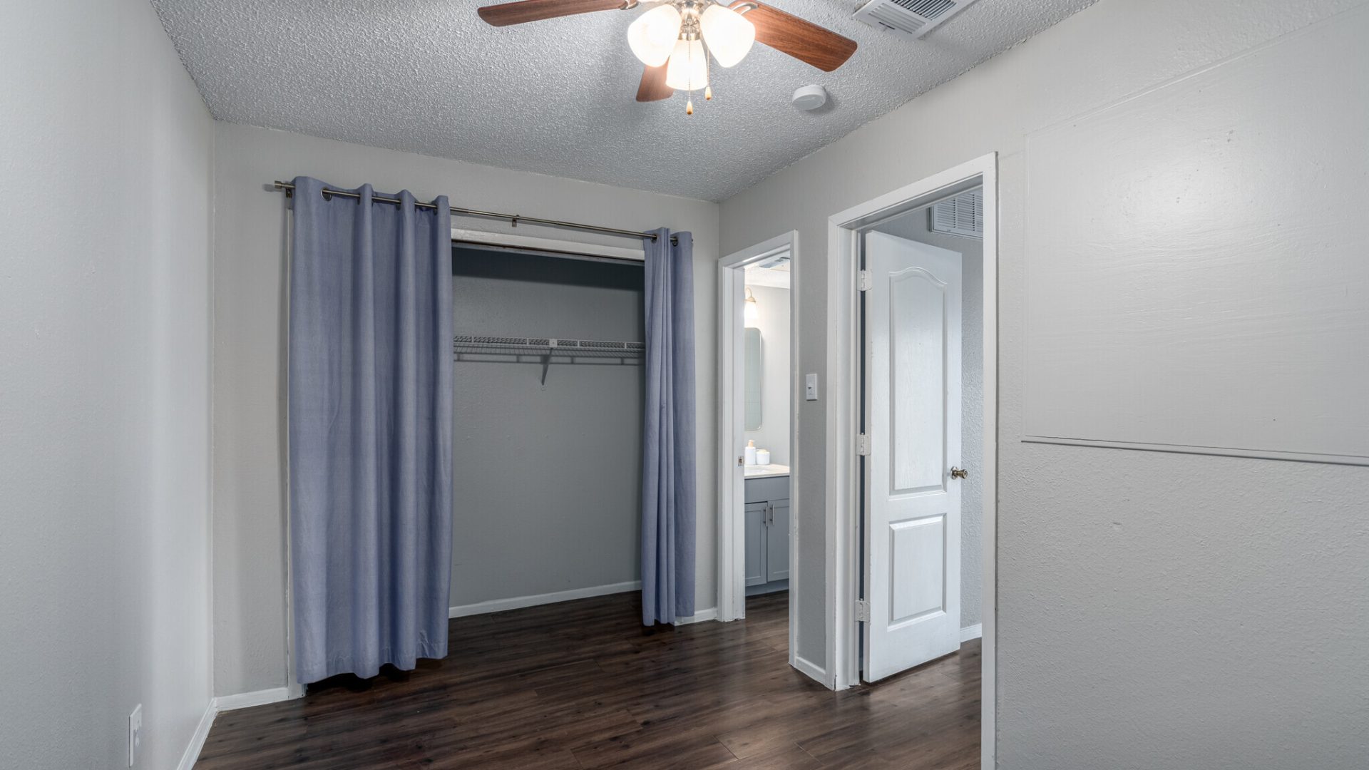 a room with a ceiling fan and hardwood floors at The Colony Creek Apartments